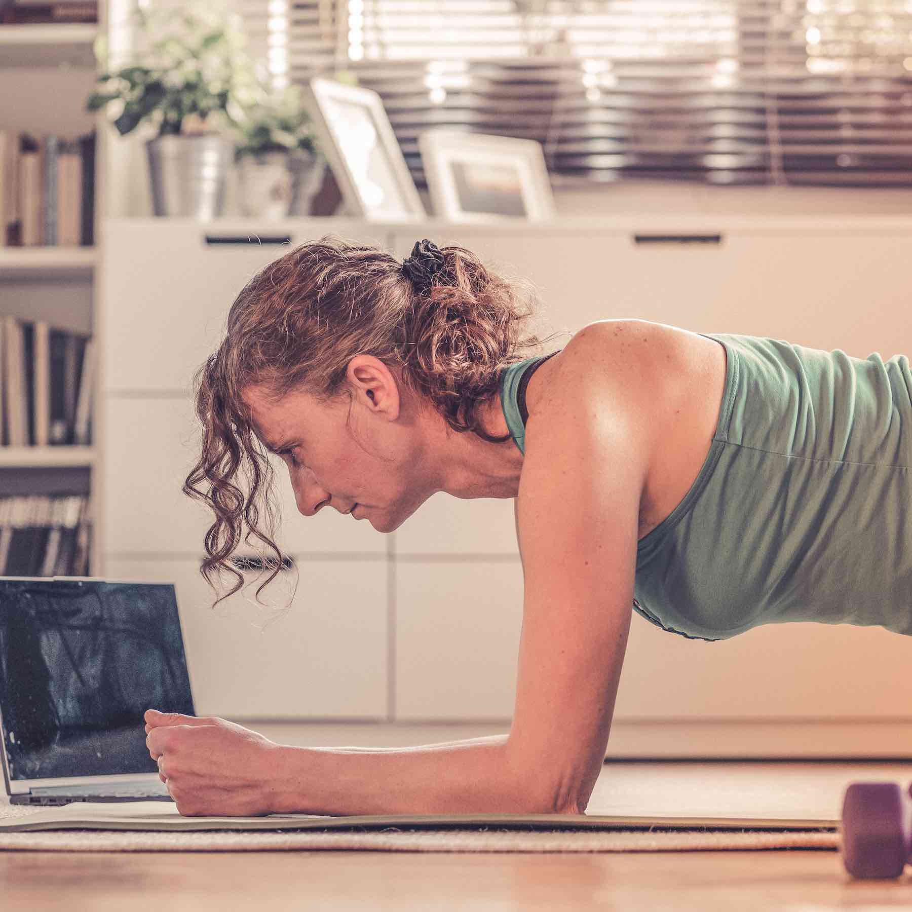 home workout concept woman in living room with  laptop and dumbells mental health in quarantine