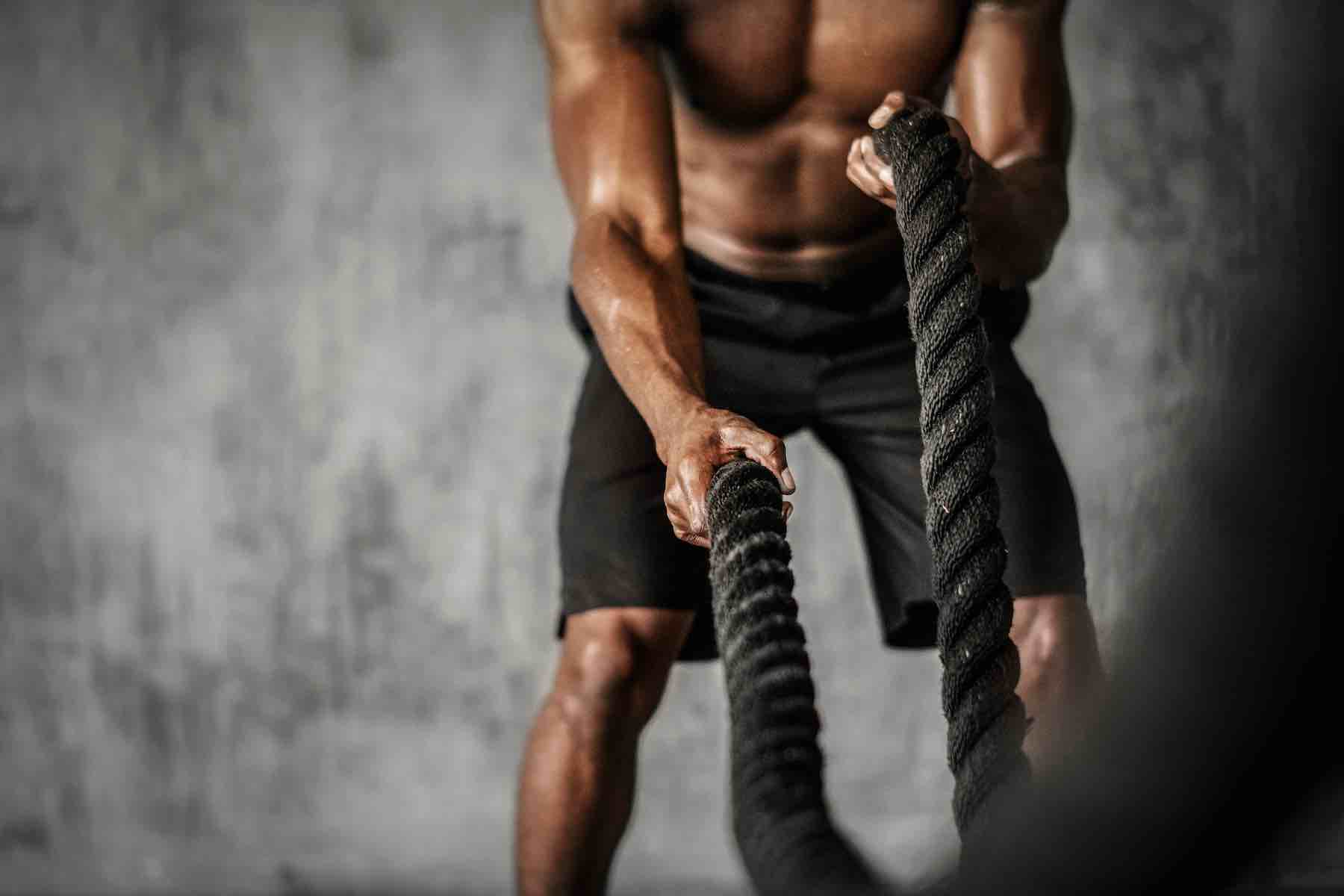 Muscular man working out on the battle ropes in a gym