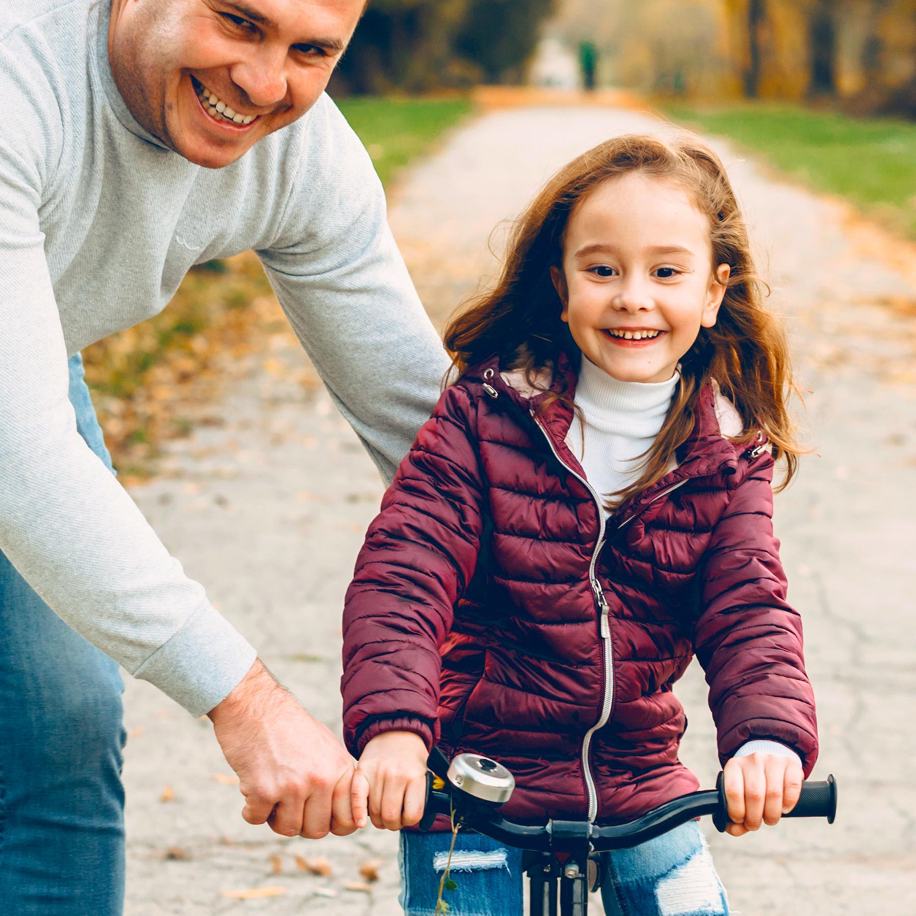 Lovely little girl learning to ride a bicycle with her father outdoor in the park.