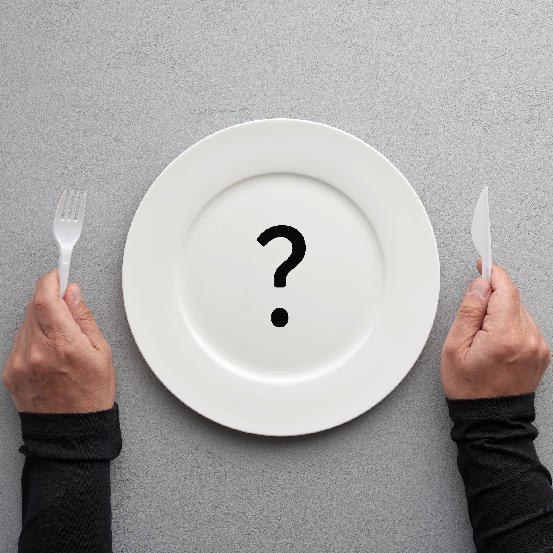 Round white plate with a question mark symbol with hands holding fork and knife. Dieting, weight loss or menu selection concept.