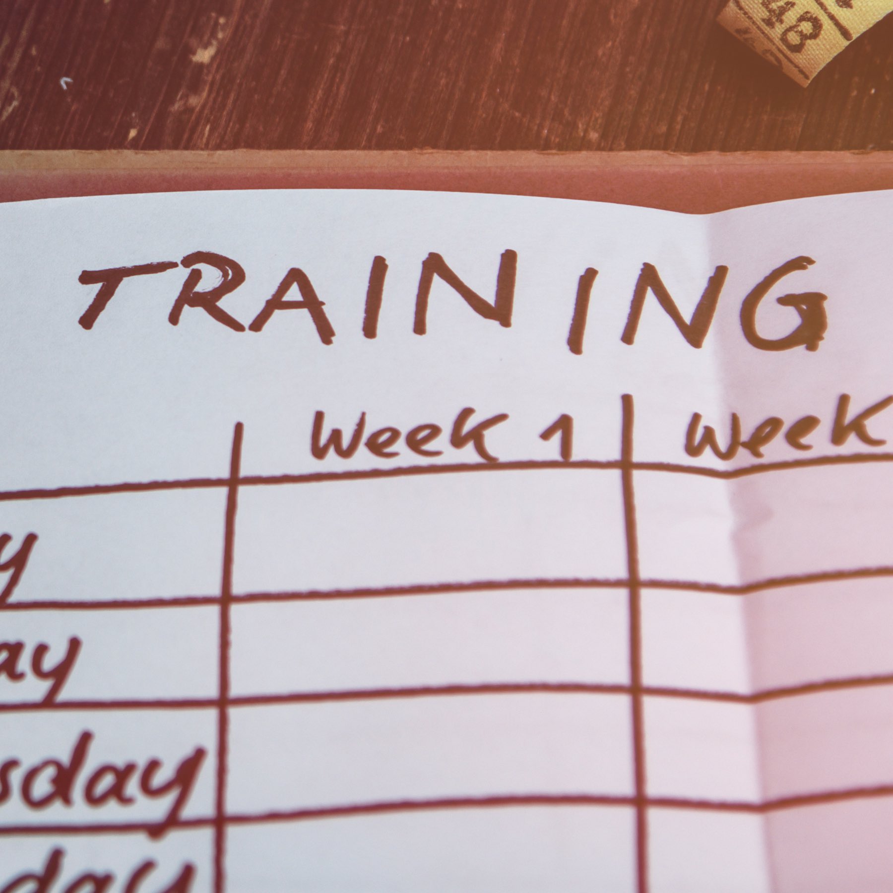 High Angle View Of A Workout Plan In Notebook At Wooden Desk with dumbbell, bottle and tape measure