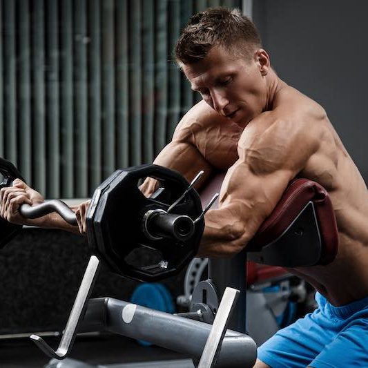 Muscular man training his arms in gym