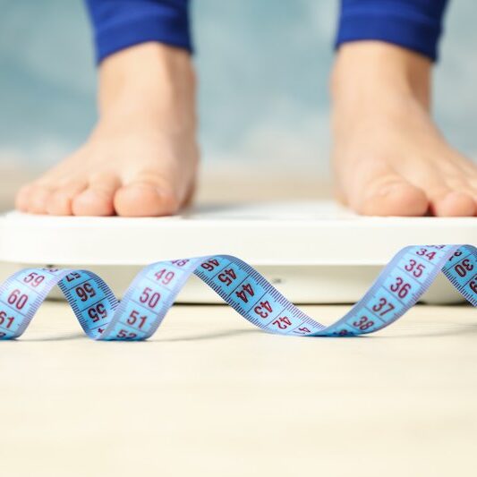 Woman stands on the scales. Measuring tape. Weight loss
